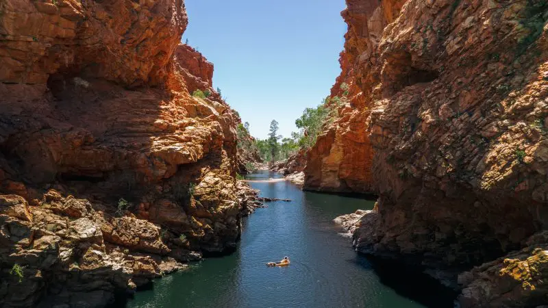 Experience a scenic river float between towering red canyon walls on a 4 Day Uluru to Alice Springs adventure tour in Australia.