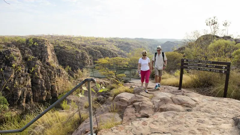 Adventurers hike a rugged trail beside stunning cliffs, ideal for pre- or post-1 Day Katherine Gorge Cruise and Edith Falls Escape.