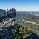 Travellers stand on a rocky lookout, admiring panoramic views along the 3 Day Great Ocean Road Grampians Explorer tour from Melbourne.