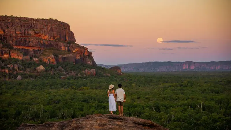 Couple on rocky ledge at sunset, beginning 4 Day Kakadu and Katherine Gorge adventure tour from Darwin, Australia’s Top End.