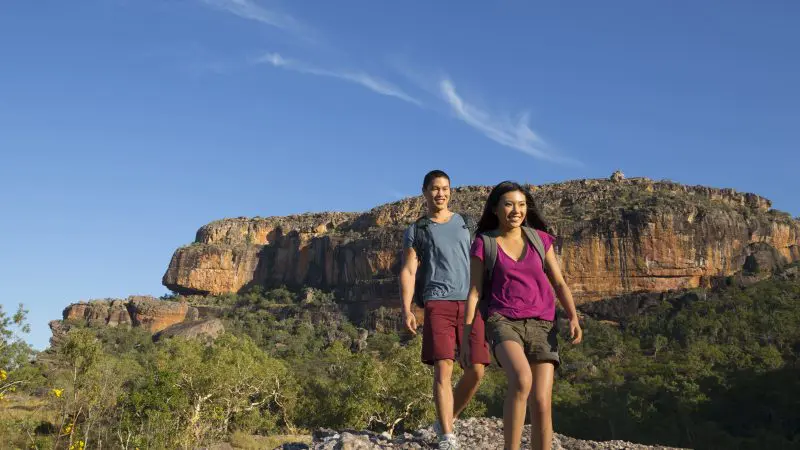 Adventurers hiking a rocky trail under clear blue skies on the 3 Day Kakadu Litchfield National Park 4WD Safari Tour, Australia.