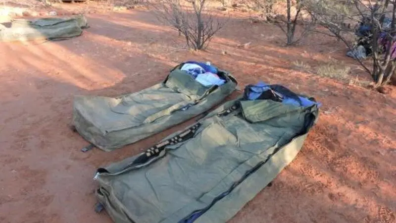 Two green swag sleeping bags lie on rich red earth, showcasing a genuine 2 Day Red Centre Rock Tour adventure from Alice Springs.