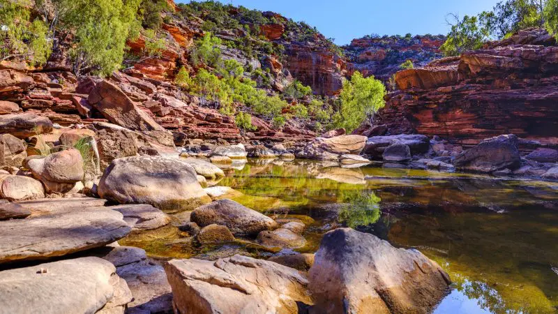 Stunning rocky gorge with vibrant red cliffs and crystal-clear pool, captured on a 4 Day Perth to Monkey Mia Coastal Loop Return Tour.