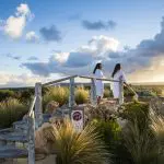 Two women in white spa robes relax at sunset after a 1 Day Peninsula Hot Springs Spa Entry Shuttle Bus experience, serene backdrop.