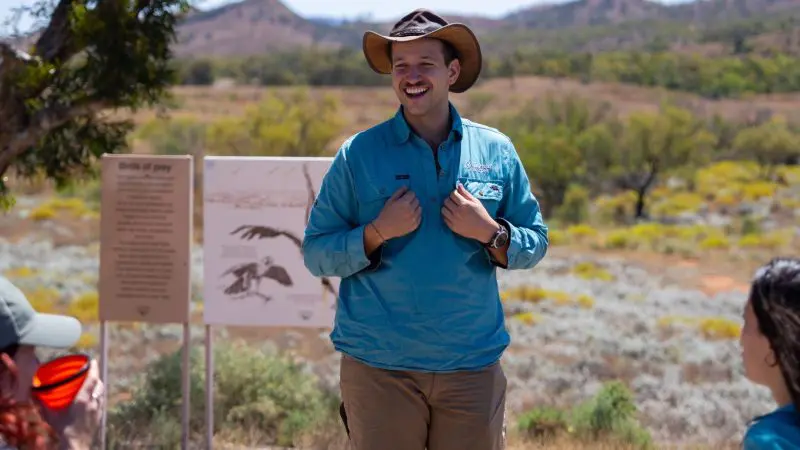 Smiling man in a hat shares captivating stories during the 7 Day Adelaide to Uluru Adventure with Untamed Escapes tour group.