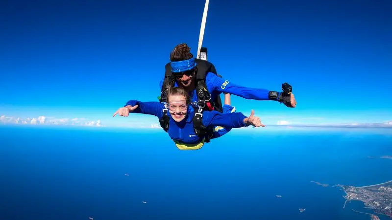 Experience the thrill of a Wollongong 15,000ft tandem skydive over stunning ocean views, with coastline and sky in the background.