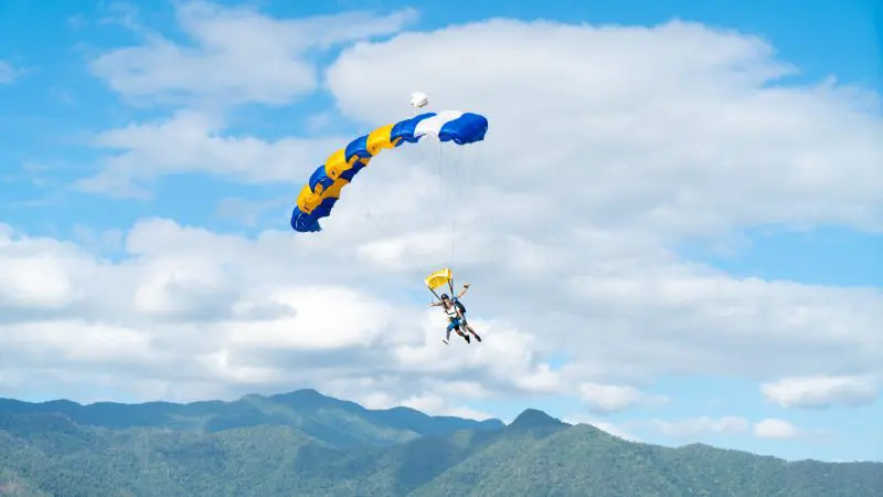Experience the thrill of a Wollongong 15,000ft tandem skydive above lush green mountains and scenic clouds for an unforgettable adventure.