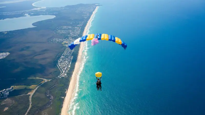Experience the thrill of a 15,000ft Skydive Noosa tandem jump, soaring above stunning coastline, blue ocean, sandy beach and lush countryside.