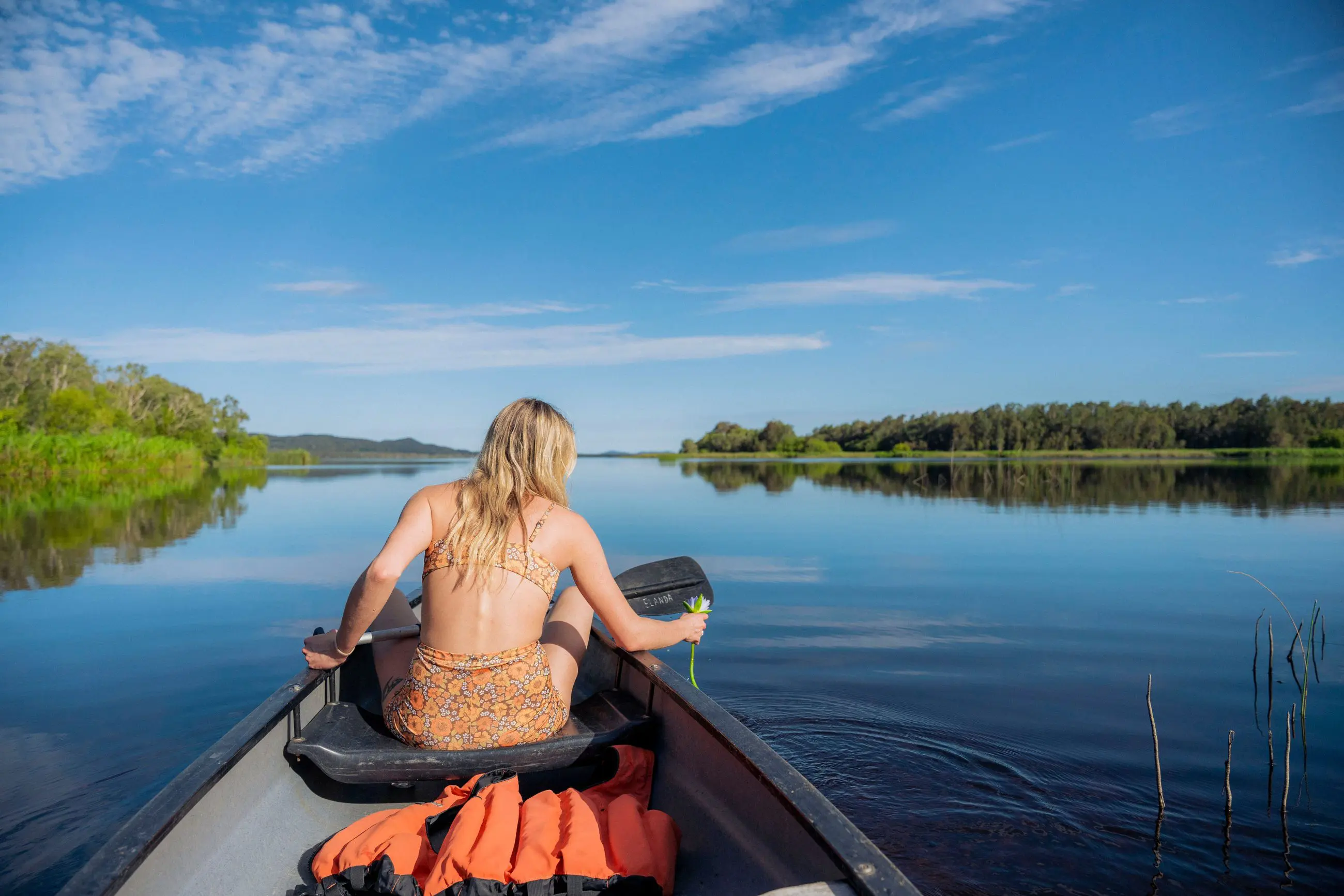 Woman paddling canoe on tranquil Noosa Everglades lake during 1 Day Explorer tour with Everglades Eco Safaris, scenic wilderness experience.