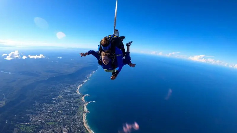 Experience the thrill of a Wollongong Up To 15,000Ft Tandem Skydive as two people soar above the pristine coastline and blue sea.