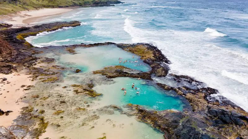 Stunning aerial view of crystal-clear natural rock pools beside the sea on a 28 Day Oz East Coast Adventure Intro Travel tour.