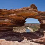 Dramatic natural rock arch overlooking winding river and rugged terrain on 10 Day Broome to Perth West Coast Adventure tour.