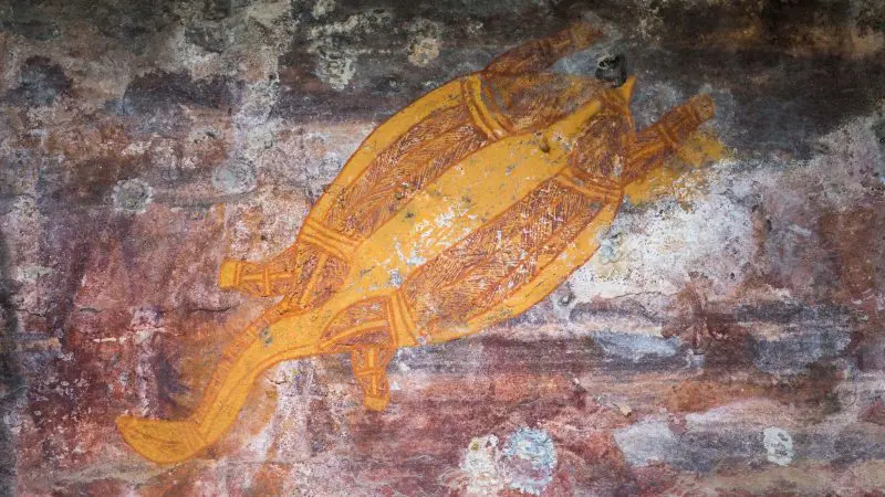 Discover ancient Aboriginal rock art depicting a vibrant yellow turtle with intricate patterns, found on a Kakadu Katherine Litchfield tour.