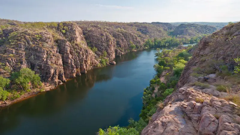 Discover a wide river winding past rugged rocky cliffs and lush green trees on a 4 Day Kakadu, Katherine & Litchfield Adventure tour.