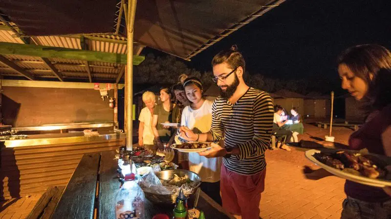 Travellers savour a gourmet buffet at a scenic outdoor event during a 3-night Uluru adventure from Alice Springs to Yulara.