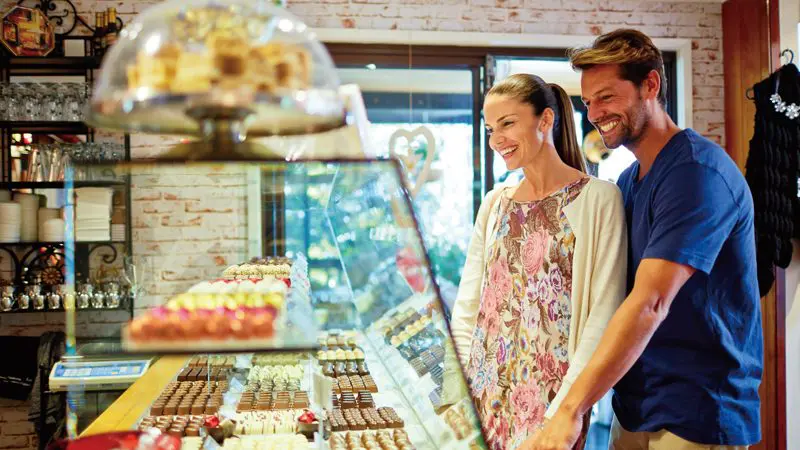 Happy couple explores artisan chocolates in a warm, inviting shop near O’Reilly’s Lamington National Park, Gold Coast.