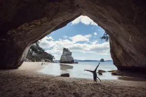 Image of a Joyful person doing a cartwheel on a beach in New Zealand during their Kiwi Experience on the Jandal Classic tour 