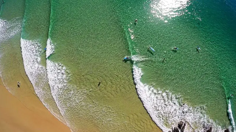 Stunning aerial shot of surfers catching Noosa’s legendary long wave, ideal for surf lessons or thrilling 4x4 coastal adventures.