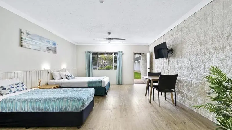 Spacious hotel room with double and single beds, flat-screen TV, work table, and large window—ideal stay before Kgari 2 Day Tour.