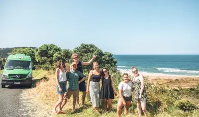Smiling group of friends posing for a photo during their Grand Kiwi Experience adventure in New Zealand’s stunning outdoors.