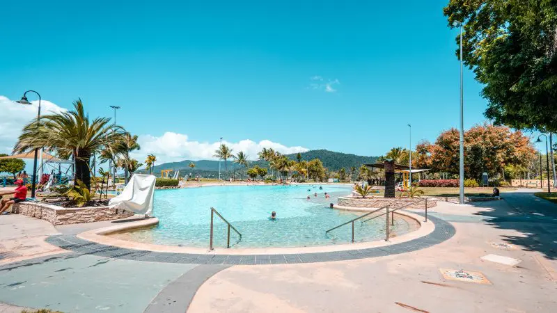 Expansive outdoor lagoon with crystal-clear water on the Ultimate East Coast Sydney to Cairns tour, scenic mountains in background.