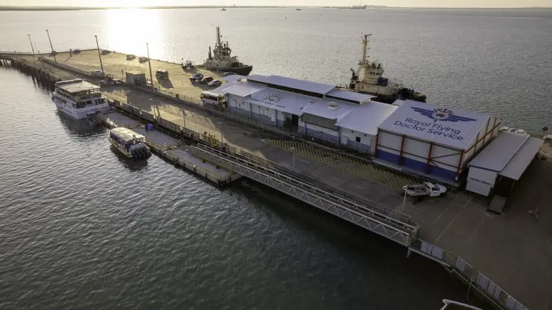 Drone shot of waterfront quay with boats and RFDS Darwin Aviation Attraction Combo Ticket building at sunset in Darwin, Australia.