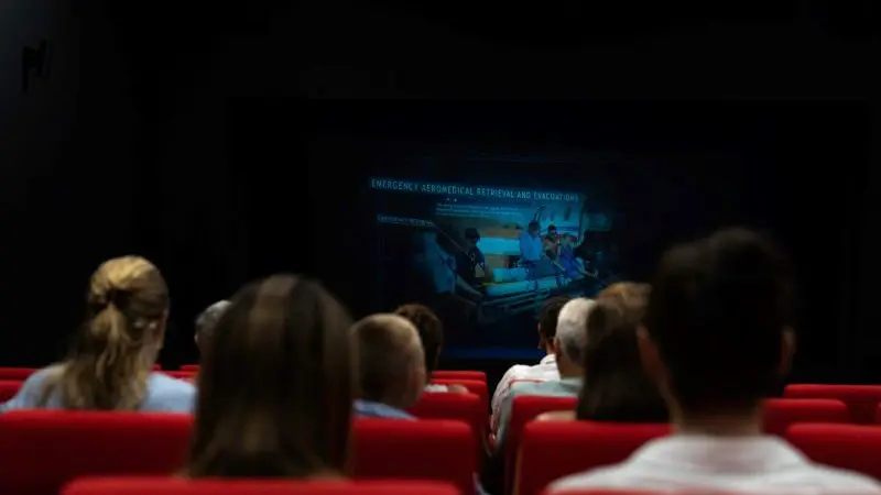 Visitors seated in a dark theatre watch a captivating film, fully immersed in the RFDS Darwin Aviation Attraction Combo Ticket experience.