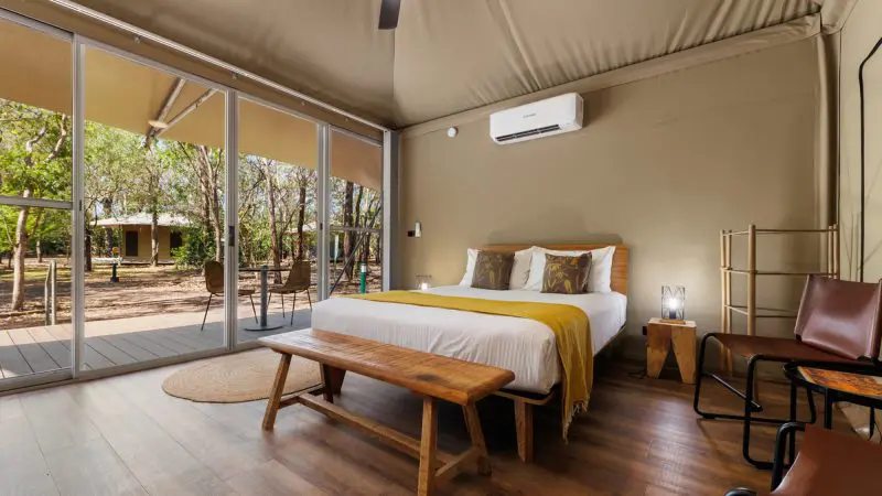 Luxurious glamping tent with plush double bed, elegant wooden furnishings, and stunning forest views on 2 Day Kakadu Outback Retreat from Darwin.