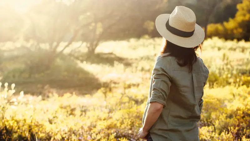 Traveller in a hat stands in a glowing field, envisioning the ultimate 4 Day Perth to Monkey Mia Coastal Loop Return Tour adventure.