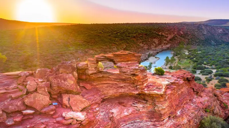 Breathtaking sunset over rugged red rock formations and winding river on a 4 Day Perth to Monkey Mia Coastal Loop Return Tour.
