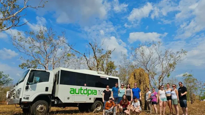 Travellers stand by an Autopia Tours 4WD bus on the 3 Day Kakadu Litchfield National Park Safari Tour beneath clear blue skies.