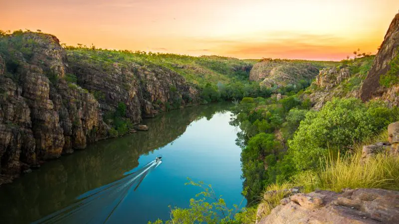 A small boat cruises a scenic river on a 5-Day Kakadu, Katherine Gorge & Litchfield 4WD Adventure tour departing from Darwin.