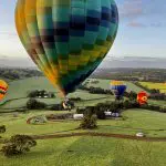 Vibrant hot air balloons soar over Avon Valley’s scenic fields at sunrise during the popular Balloon Flight With Breakfast Perth experience.