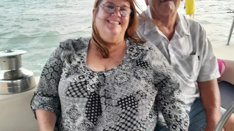 Happy couple enjoys a Townsville Lunchtime Sailing Private Charter, with scenic water views and lush hills in the background.