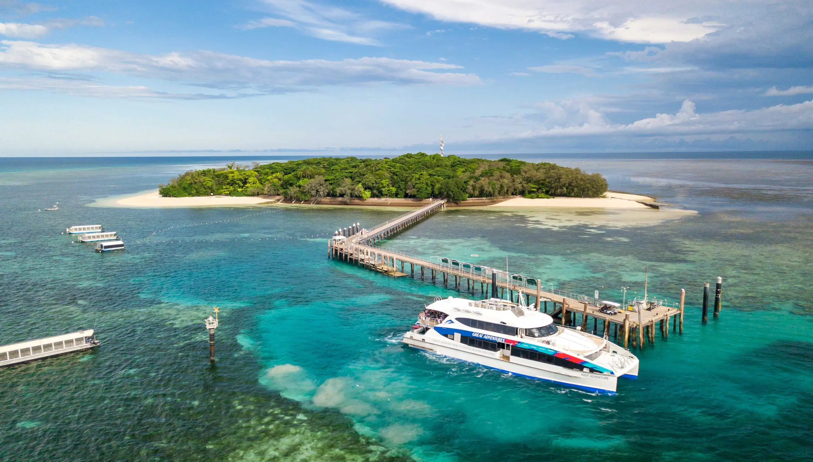 White boat at Green Island pier over crystal-clear turquoise water, ideal for snorkelling or glass-bottom boat tours in Australia.