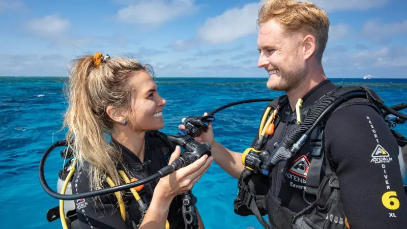 Two happy scuba divers exchange smiles on the Silverswift Outer Barrier Reef cruise boat, ready for an unforgettable diving adventure.