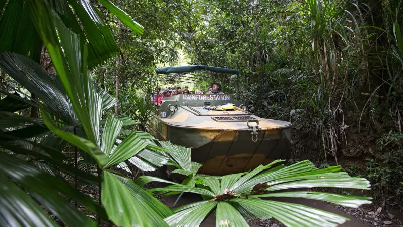 Kuranda Deluxe Scenic Railway tour group explores lush green rainforest in a bright yellow amphibious vehicle for an unforgettable adventure.