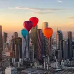 Soar above Melbourne’s skyline at sunrise as four colourful hot air balloons drift peacefully—book your unforgettable 1-hour flight now!.
