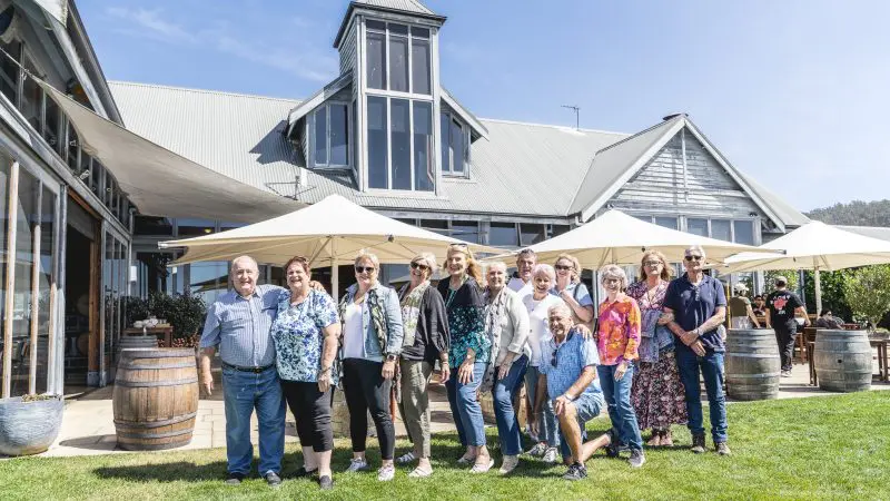 Smiling group of friends gathers outside a grand estate on a Coal River Valley Wine and Gin Safaris Private Day Tour in Tasmania.