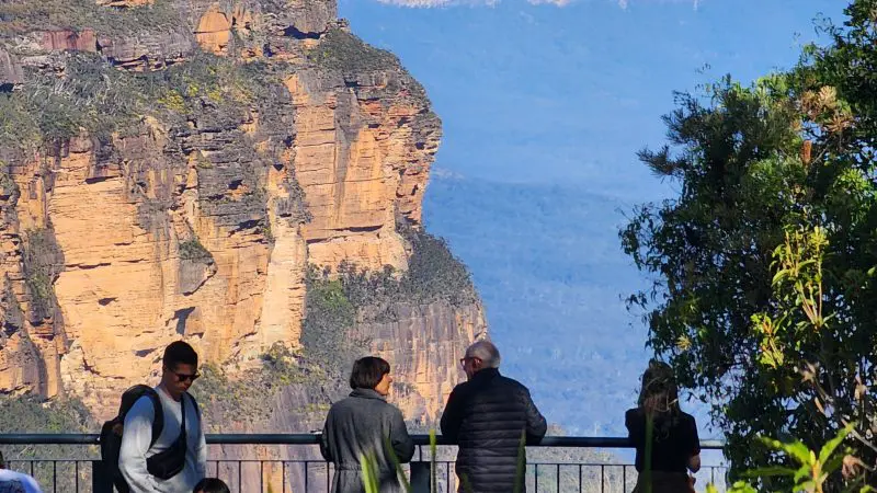 Group of four at panoramic Blue Mountains lookout on guided day tour with waterfall walk and social lunch, stunning scenic views.