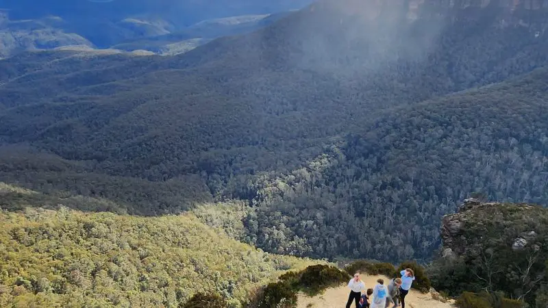 Group of four exploring a rocky Blue Mountains lookout on a guided day tour featuring scenic waterfall walk and sociable lunch experience.
