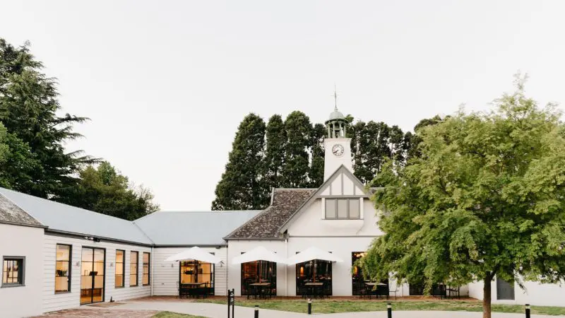 Elegant building with a clock tower, lush trees, and outdoor seating—ideal setting for gourmet wine tasting lunch and premium gin tasting.