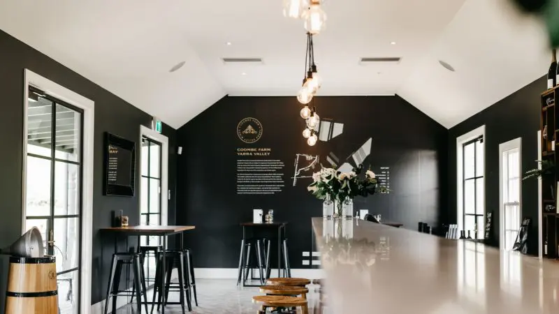 Chic winery tasting room with dramatic black walls, elegant floral counter, and stylish bar stools—ideal for gourmet wine tasting events.