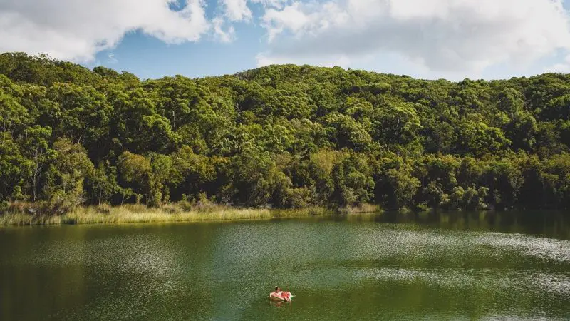 Discover ultimate relaxation as a traveller lounges on a pink float in a serene green lake during the calming Kgari 4 Day Experience.