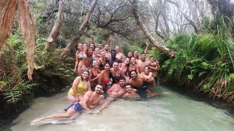 Energetic group in swimming costumes poses and smiles on Fraser Island during a 4WD camping adventure with Island Expeditions Kgari Tours.