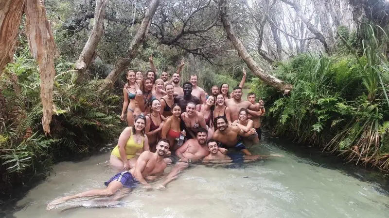 Happy group in swimwear poses in a scenic creek during a Kgari Safari Tour on Fraser Island, enjoying an unforgettable Australian adventure.