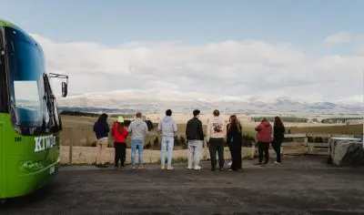 A group of hikers standing on a scenic road gazing at majestic mountain peaks under a clear sky, perfect for outdoor adventure seekers.