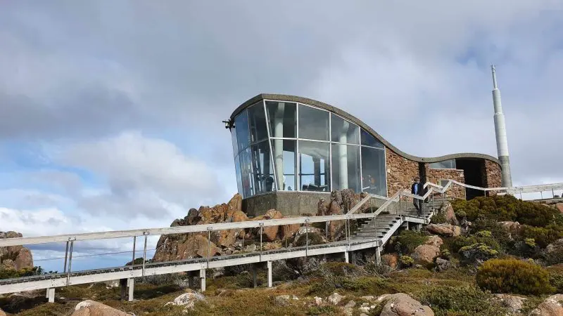 Stunning modern glass observatory perched on a rugged rocky hill, offering breathtaking panoramic views like Gordon Dam Lake Pedder tours.