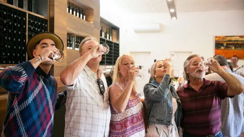 Five adults enjoying premium Barossa Valley wine tasting, sipping select wines together in a sunlit tasting room on a guided tour.