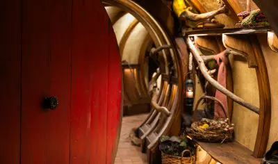 Step through a round red door into a charming Hobbiton Movie Set hallway, a must-see highlight for unforgettable movie set tours.
